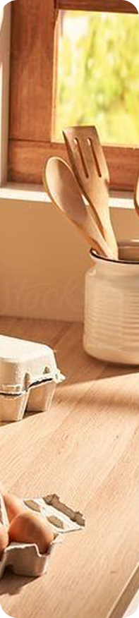 Kitchen utensils, egg carton, and wooden spoons on a wooden counter