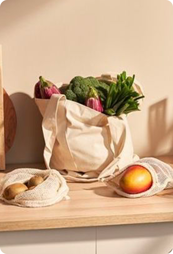 Tote bag full of fresh vegetables with mesh produce bags on wooden counter